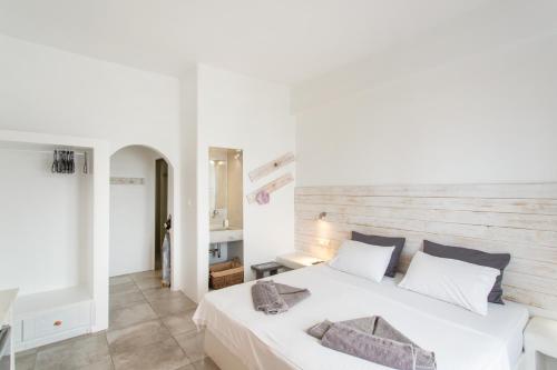 a bedroom with a white bed with a wooden headboard at Irini Rooms in Naousa