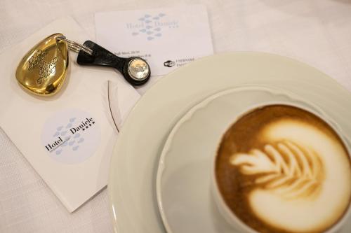 a cup of coffee on a plate next to a spoon at Hotel Daniele in Lignano Sabbiadoro