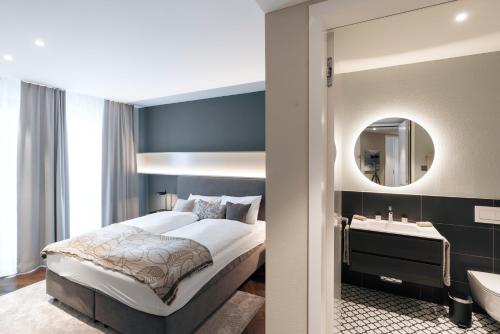 a bedroom with a bed and a sink and a mirror at Andermatt Alpine Apartments in Andermatt