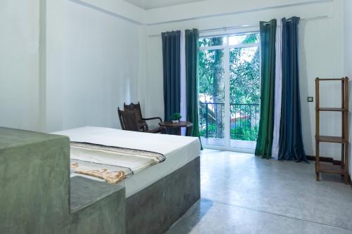 a bedroom with a bed and a large window at Hotel Kurulu Garden in Ahungalla