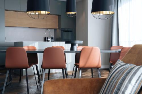 a kitchen with a table and orange chairs at Andermatt Alpine Apartments in Andermatt