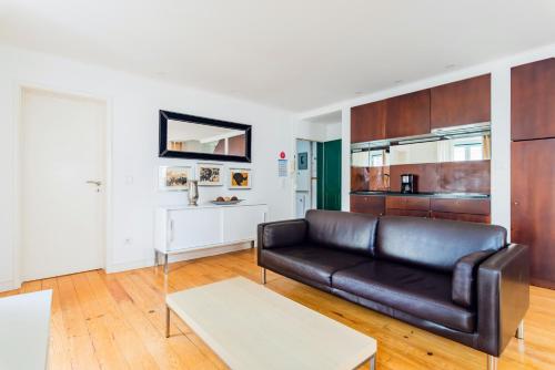 een woonkamer met een leren bank en een tafel bij Condessa Central Duplex in Lissabon