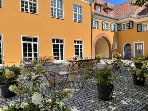 une cour avec des tables et des chaises et un bâtiment dans l'établissement Piesteritzer Hof - Hotel Garni, à Wittemberg