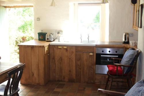una cocina con armarios de madera y fregadero en Relaxing 2-Bed Cottage in Rhandirmwyn, en Llandovery