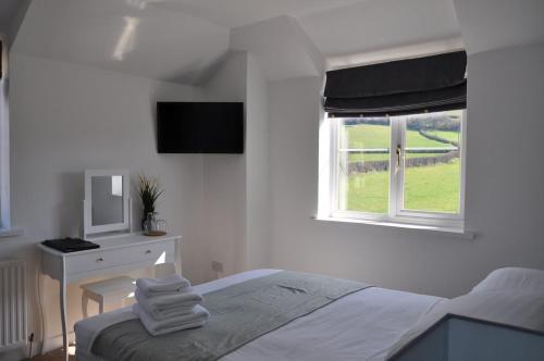 a bedroom with a bed and a desk and a window at The Lodge by Cefn Tilla in Usk