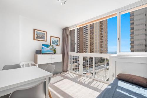 a bedroom with a bed and a desk and a large window at Bacana 3-3 Apartment Levante Beach in Benidorm