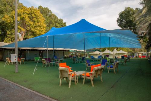 a large blue tent with chairs and tables under it at The Camping Site Hamat Gader in Kinneret