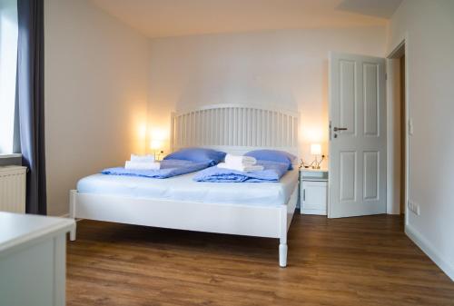 a white bed with blue pillows in a bedroom at Schleiblick App 17 in Rabenkirchen-Faulück
