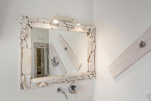 a mirror hanging on a wall next to a sink at Irini Rooms in Naousa