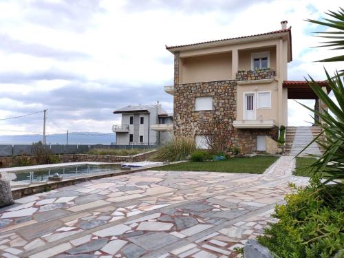 a house with a stone patio next to a building at Dimitris Vaso’s Villa with Sea and Mountain View! in Aliveri