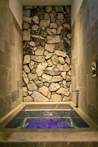 a bath tub with a stone wall in a bathroom at Anděl Penzion & Cafe in Rožnov pod Radhoštěm