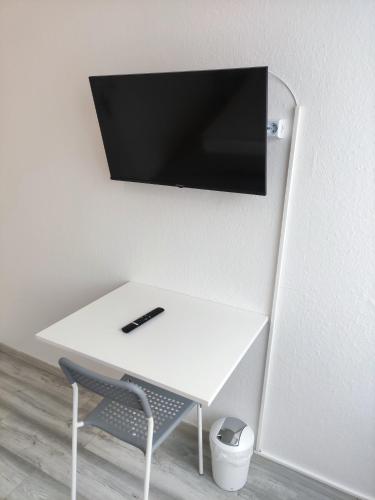a white desk with a television on a wall at Gästehaus am Bahnhof, Self-Check-In in Vechta