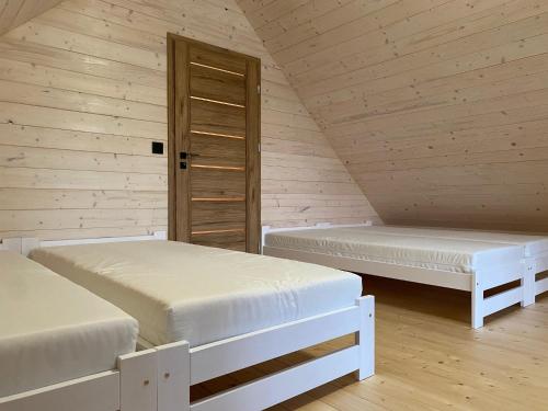 2 łóżka w pokoju z drewnianymi ścianami w obiekcie Mazurskie Klimaty - domy z widokiem w mieście Tomaszkowo
