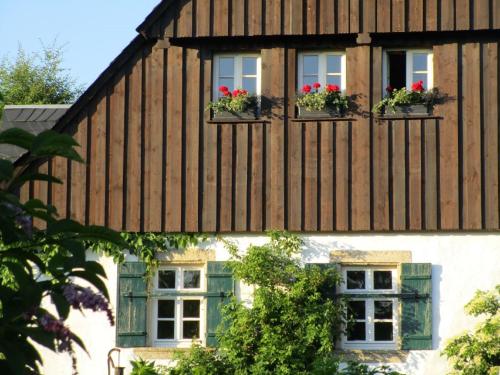 a wooden house with two windows and flowers in window boxes at Austragshaus Almbranz in Helmbrechts