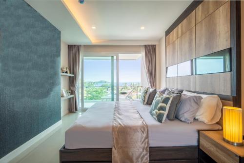 a bedroom with a large bed with a large window at Babylon Sky Garden in Rawai Beach