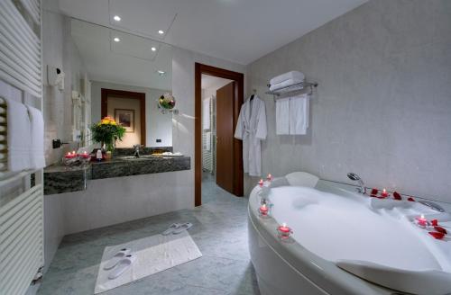 a white bathroom with a tub and a sink at Phi Hotel Cavalieri in Bra