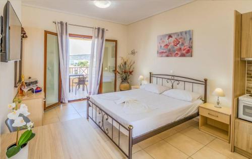 a bedroom with a large bed and a balcony at Aloustina Apartments in Archangelos