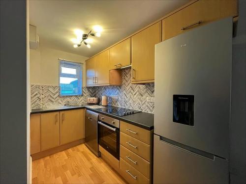a kitchen with wooden cabinets and a refrigerator at Cotswold apartment with private parking! in Stow on the Wold