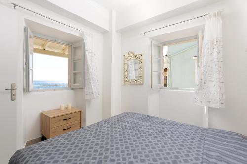 a white bedroom with a bed and two windows at Salt & Sun Apartments by Konnect, at Kaminaki Beach in Nisaki