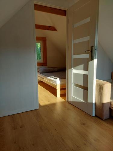 an open door to a bedroom with a bed at Słoneczny domek ze stawem i wędkowaniem in Żdżary