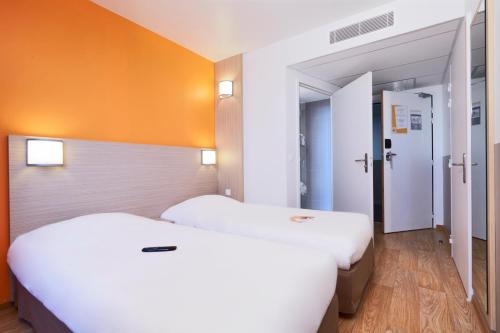 two beds in a room with orange walls at Premiere Classe Bordeaux Ouest - Mérignac Aéroport in Mérignac