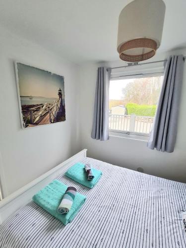 a bedroom with a bed with two towels and a window at 147 Snowdon Drive, Glan Gwna in Caernarfon