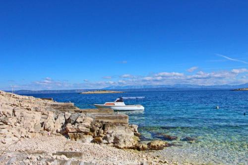 a boat in the water next to a rocky shore at Apartments Sea Line in Prigradica