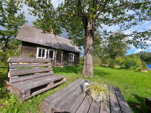 una casa antigua con un árbol y una mesa de madera en Lauku māja Riesti, 