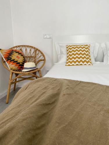 a bedroom with a large bed and a chair at Casas dos Seixos in Moledo
