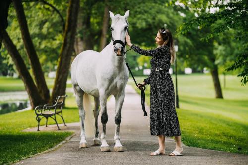 a woman standing next to a white horse at Elegans Hotel Brdo in Kranj