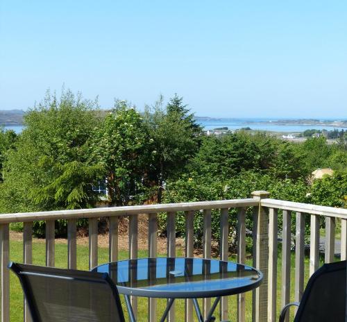 a table and chairs on a deck with a view of the water at Aultbea Lodges in Aultbea