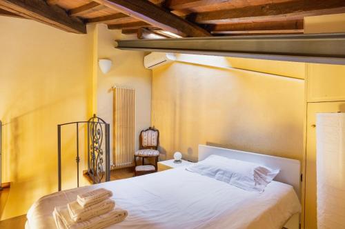 1 dormitorio con 1 cama con sábanas blancas y silla en Cozy classic Italian house near Santa Croce, on the Lungarno, en Florencia