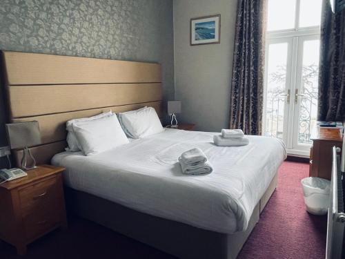 a bedroom with a large bed with towels on it at Merrion Hotel in Llandudno