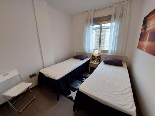 dwa łóżka w małym pokoju z oknem w obiekcie La Manga Beach Club - A w mieście La Manga del Mar Menor