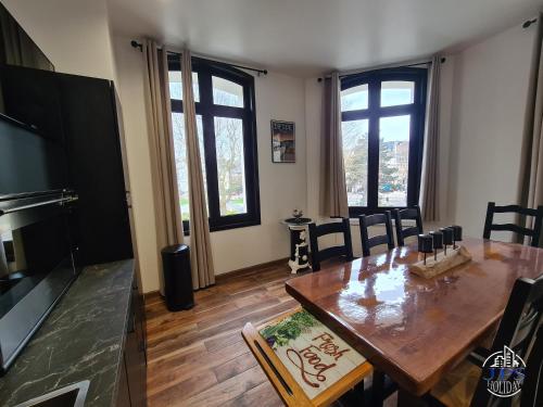 uma sala de jantar com mesa, cadeiras e janelas em Quintessence By JPS Holiday, Splendide appartement au coeur de Dieppe em Dieppe