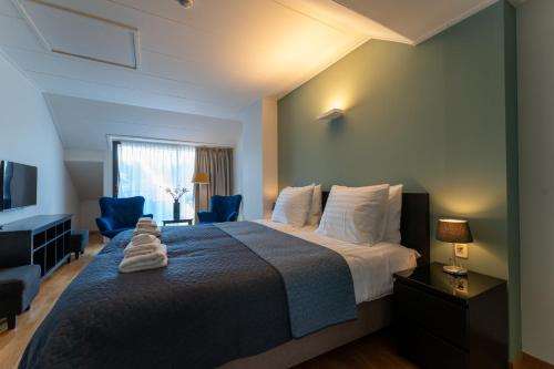 a bedroom with a large bed with two blue chairs at Hof van Slenaken - Hotel & Apartments in Slenaken