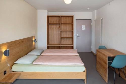 a bedroom with a bed and a desk and a bed sidx sidx sidx at Crans-Montana Youth Hostel in Crans-Montana