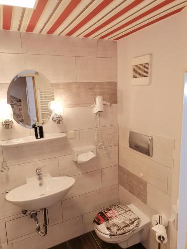 a white bathroom with a sink and a toilet at Boulevardhotel Sängerstadt - alle Zimmer klimatisiert in Finsterwalde