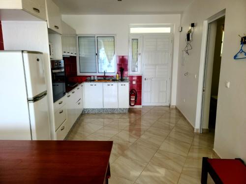 uma cozinha com armários brancos e um frigorífico vermelho em LA MENOR em Ribeira Grande