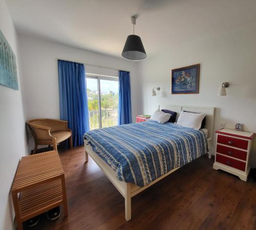 a bedroom with a bed and a window with blue curtains at Penthouse Roma in Fuzeta