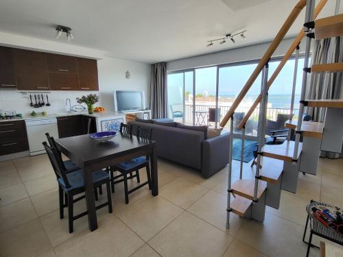a kitchen and a living room with a table and chairs at Penthouse Roma in Fuzeta