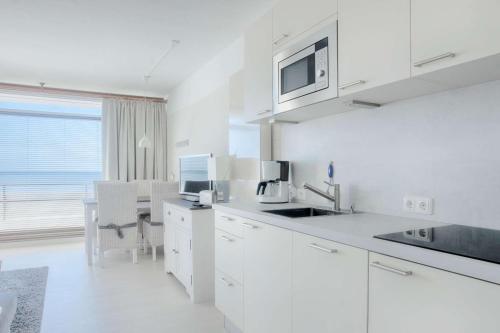 a white kitchen with a sink and a microwave at Bellevue C14 in Großenbrode