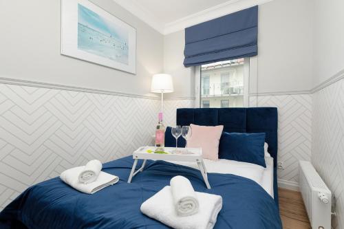 Un dormitorio con una cama azul y una mesa con toallas. en Apartamenty Osiedle Bursztynowe II by Renters, en Kołobrzeg