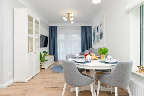 a dining room with a white table and chairs at Apartamenty Osiedle Bursztynowe II by Renters in Kołobrzeg