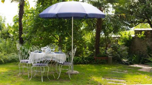 a table and chairs under an umbrella in a yard at B&B Casa Carla in Pinerolo