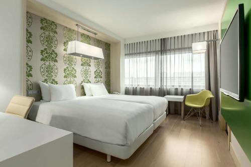 a hotel room with a large white bed and a desk at NH Amsterdam Zuid in Amsterdam