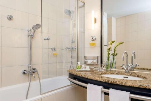 La salle de bains est pourvue d'une douche, d'un lavabo et d'une baignoire. dans l'établissement NH Potsdam, à Potsdam