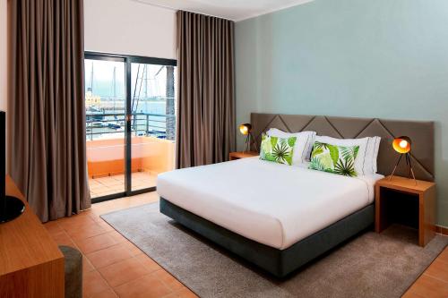 1 dormitorio con 1 cama grande y balcón en NH Marina Portimao Resort en Portimão