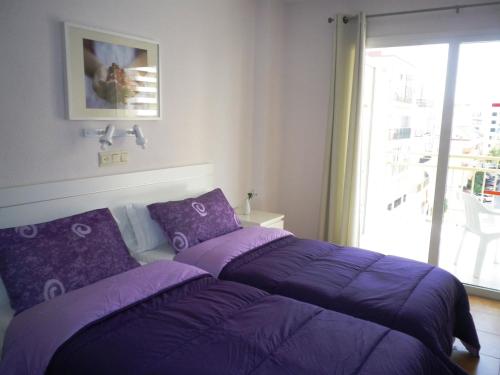 un letto viola in una camera con finestra di Apartamentos Turísticos Yamasol a Fuengirola