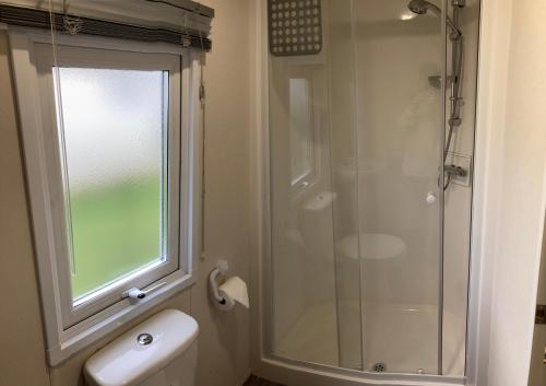 Un baño con ducha, inodoro y ventana. en Seaview Holiday Rentals, en Whitstable